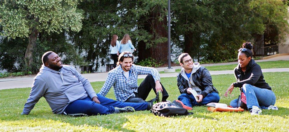 Students sitting on the grass in front of De La Salle Hall